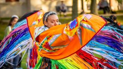 indigenous performer wearing colorful cape