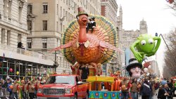 Large Turkey and Kermit the Frog floats among crowds at the Thanksgiving Day Parade in NYC.