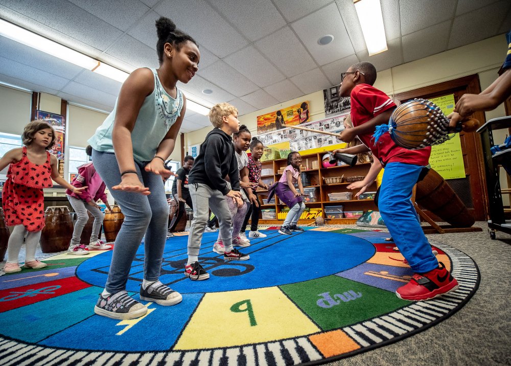 Classroom of third grade students dancing to the rhythm of West African instrument playing