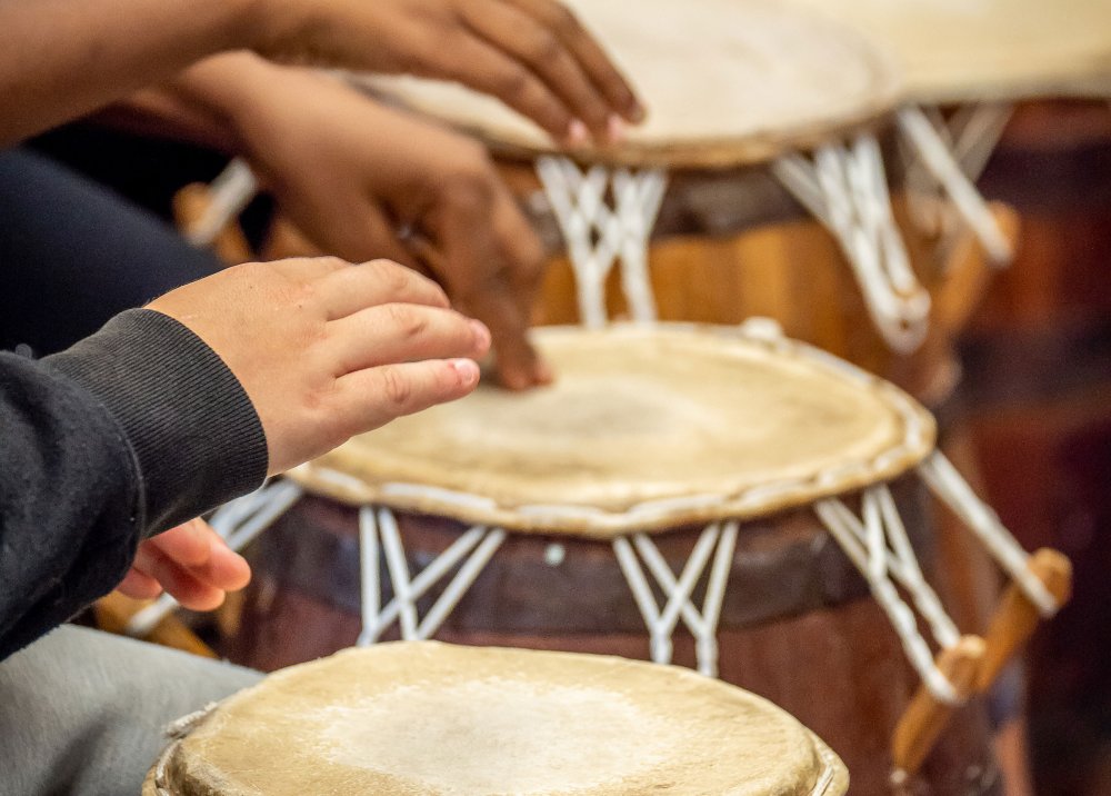 Close-up of elementary school students hands hitting West African drums