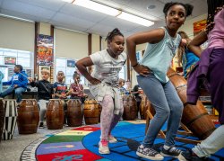Third grade students dancing and playing West African drums in classroom