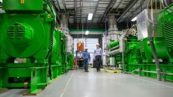 Two engineers walking between large green mechanical structures in the University's energy plant