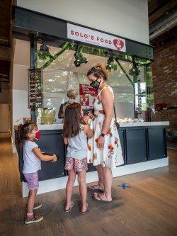 woman and children discuss what to order from Solo's Food counter