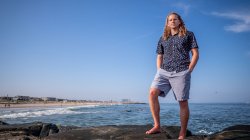 Ayre Janoff standing on rocky shore overlooking ocean