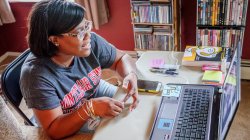 female student using laptop to video conference from her bedroom