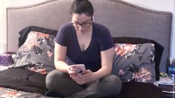 Student sitting on her bed at home texting