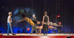 Photo of dancers on stage in modern dress doing acrobatic movements