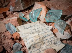 close view of elegantly written note beneath shards of glass and brick