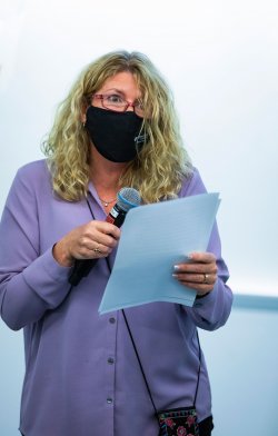 Lora Billings holding a microphone and presentation notes