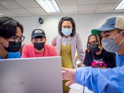 Professor Karmen Yu at a computer with students in masks.