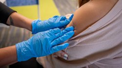 Close view of nurse applying bandage to a shoulder after vaccination shot
