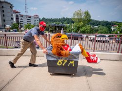 University President Jonathan Koppell pushing Montclair State mascot Rocky the Red Hawk in a rolling bin during move in
