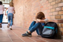 stock photo of young child in school hallway crying