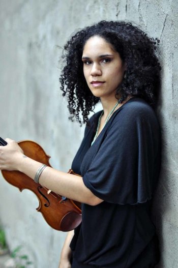 Jessie Montgomery leaning on wall holding violin