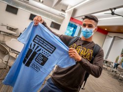 student volunteer holding up his day of service tee shirt