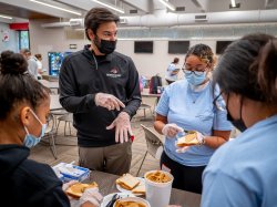 president koppell working with volunteer students making peanut butter and jelly sandwiches