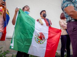 two students in attendance holding up the flag of Mexico