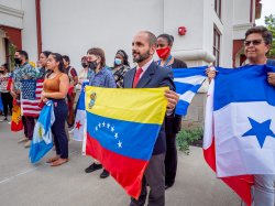 staff and students stand together holding flags, the flags of Venezuela and Uruguay in the foreground.