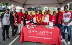 Black alumni advisory council staff poses for a photo in their informational tent