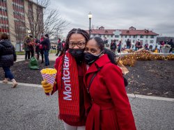 two attendees smiling behind their masks, one holds a popcorn cone