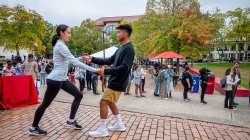 Two students dancing on the patio in front of the Student Center