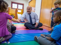 Center for Autism and Early Childhood Mental Health Director Gerry Costa on a play mat with children
