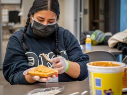 Student volunteer spreading peanut butter on sliced bread