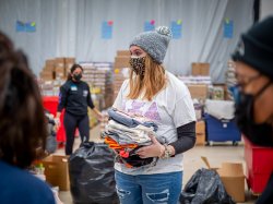 Student volunteer holding folded clothes