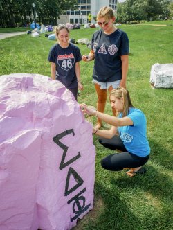 Students gathered around painted boulder