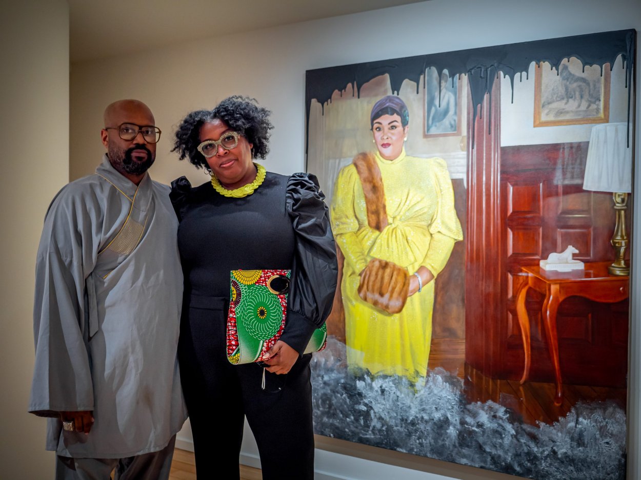 Ajamu Kojo poses with the model featured in the painting behind them.