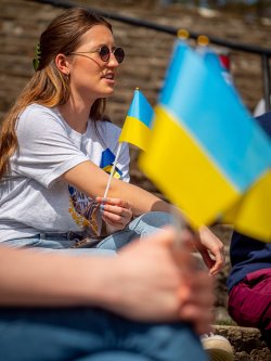 woman in amphitheater behind foreground of ukranian flags