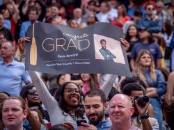 Photo of a woman in a stadium holding up a sign for her graduate, Kevin Bernard
