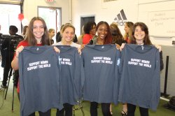 A photo of 4 Montclair State students holding up t-shirts that read "Support women, support the world"