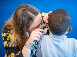 Professor Alexis Rooney inspecting a child's ear with otoscope