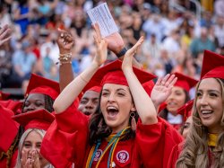 Photo of a graduate in a crowd with arms raised and cheering