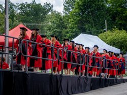 Photo of graduates lining up on a ramp in front of a stage