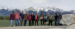 participants of the summer field geology course stand in front of a mountain range in the distance