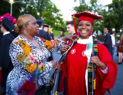 Photo of a parent with their graduate dressed in a red rob