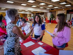 two students speaking with Professor Sandra Adams over a table at the college fair