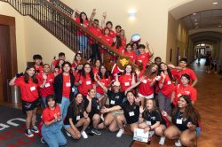 large group of students and mentors pose with Rocky on a staircase