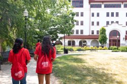 two students walking on campus wearing backpacks with HSCI logo