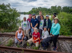 group of people smile for the camera standing on railroad tracks