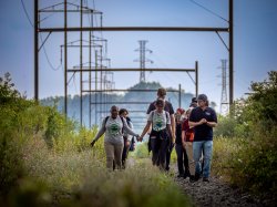 Group of people walking along overgrown railroad tracks