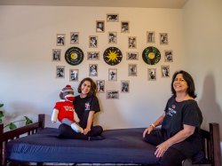 student and parent smiling for camera in front of photo collage on wall