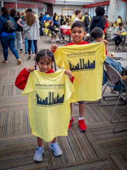 two small children holding National Day of Service t-shirts