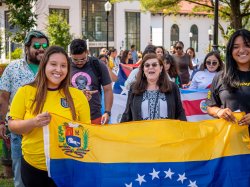 Katia Paz Goldfarb with students behind a flag