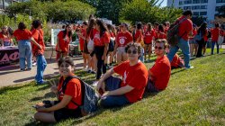 Students sitting on grass in red shirts