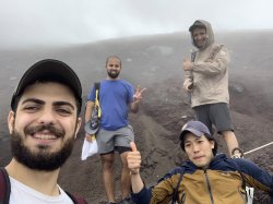 Group of four men pose for a selfie on Mount Fuji