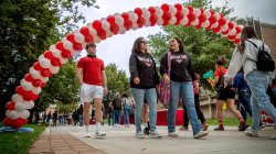 Homecoming attendees walking under balloon arch