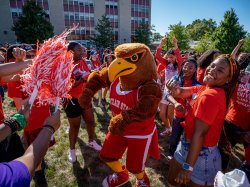 Rocky the Red Hawk dancing with students on campus